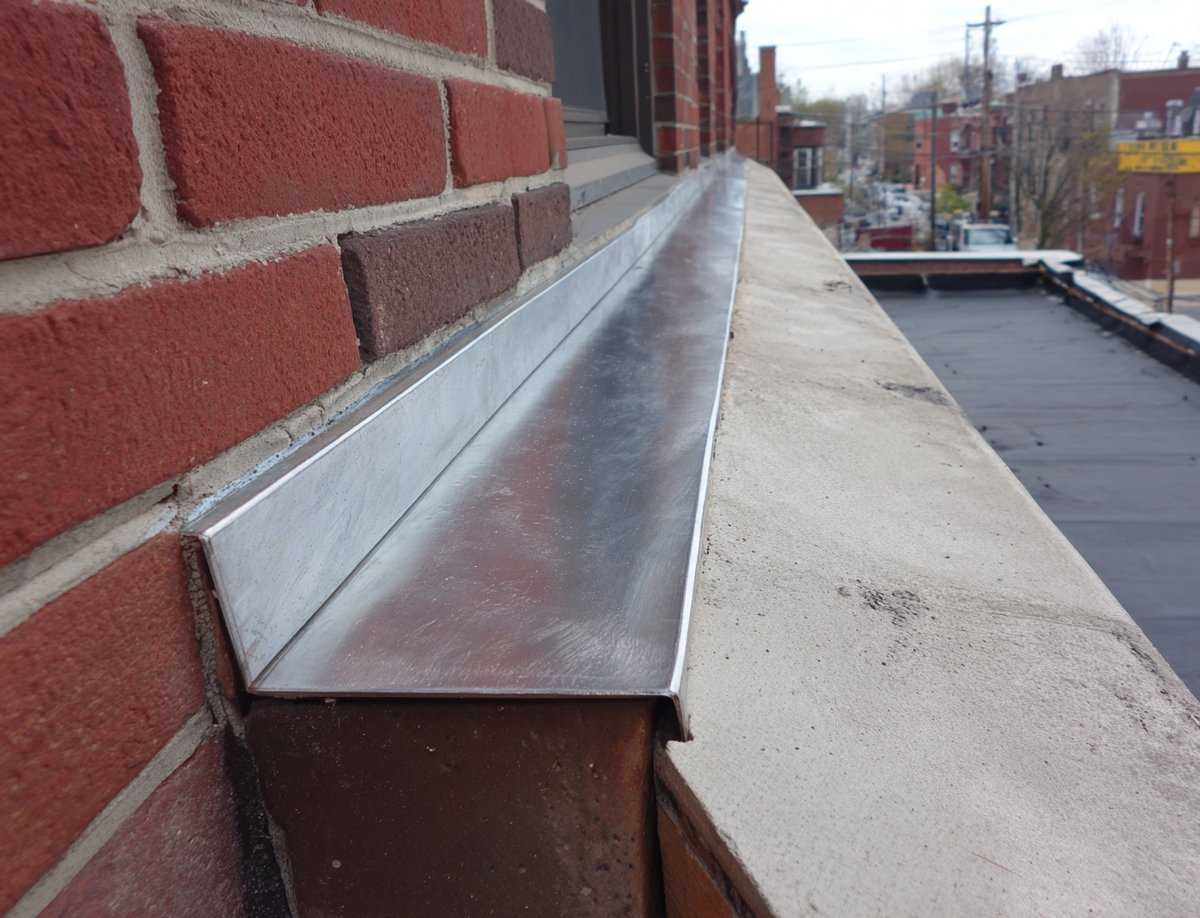 New metal counter flashing set into a cut mortar joint on a brick parapet wall in Queens
