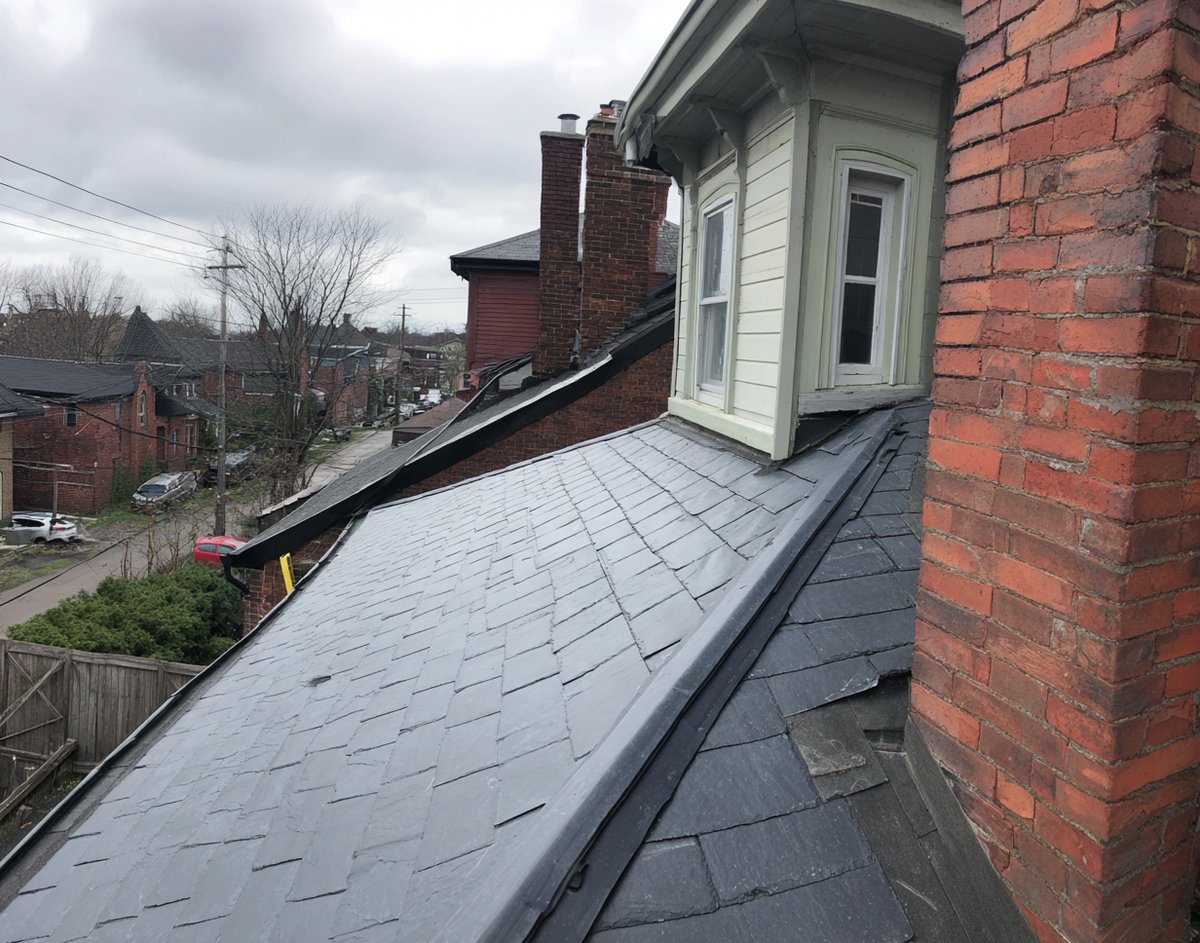 New step flashing woven along a dormer wall on a brick two-family home in Sunnyside