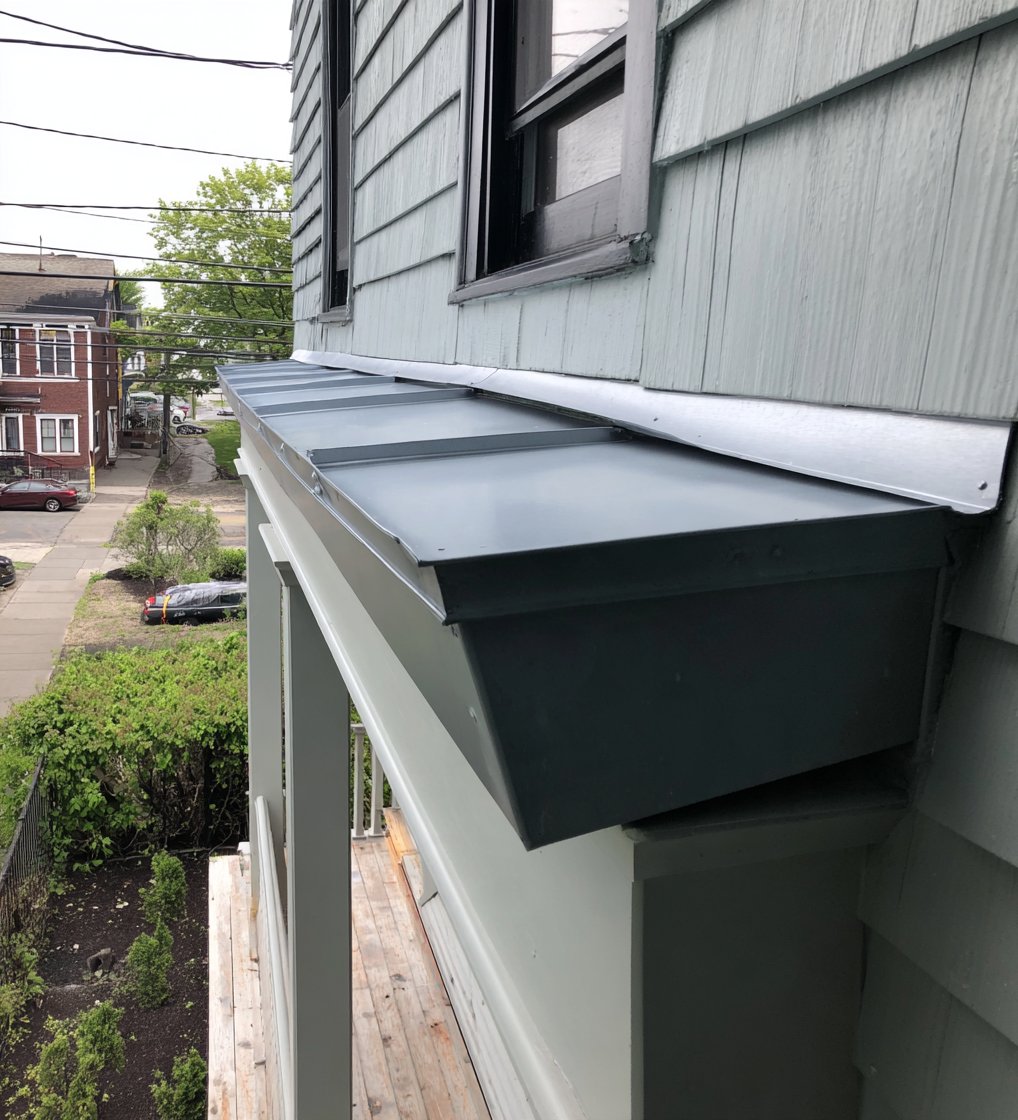 New metal counter flashing set into the house wall above a porch roof in Queens